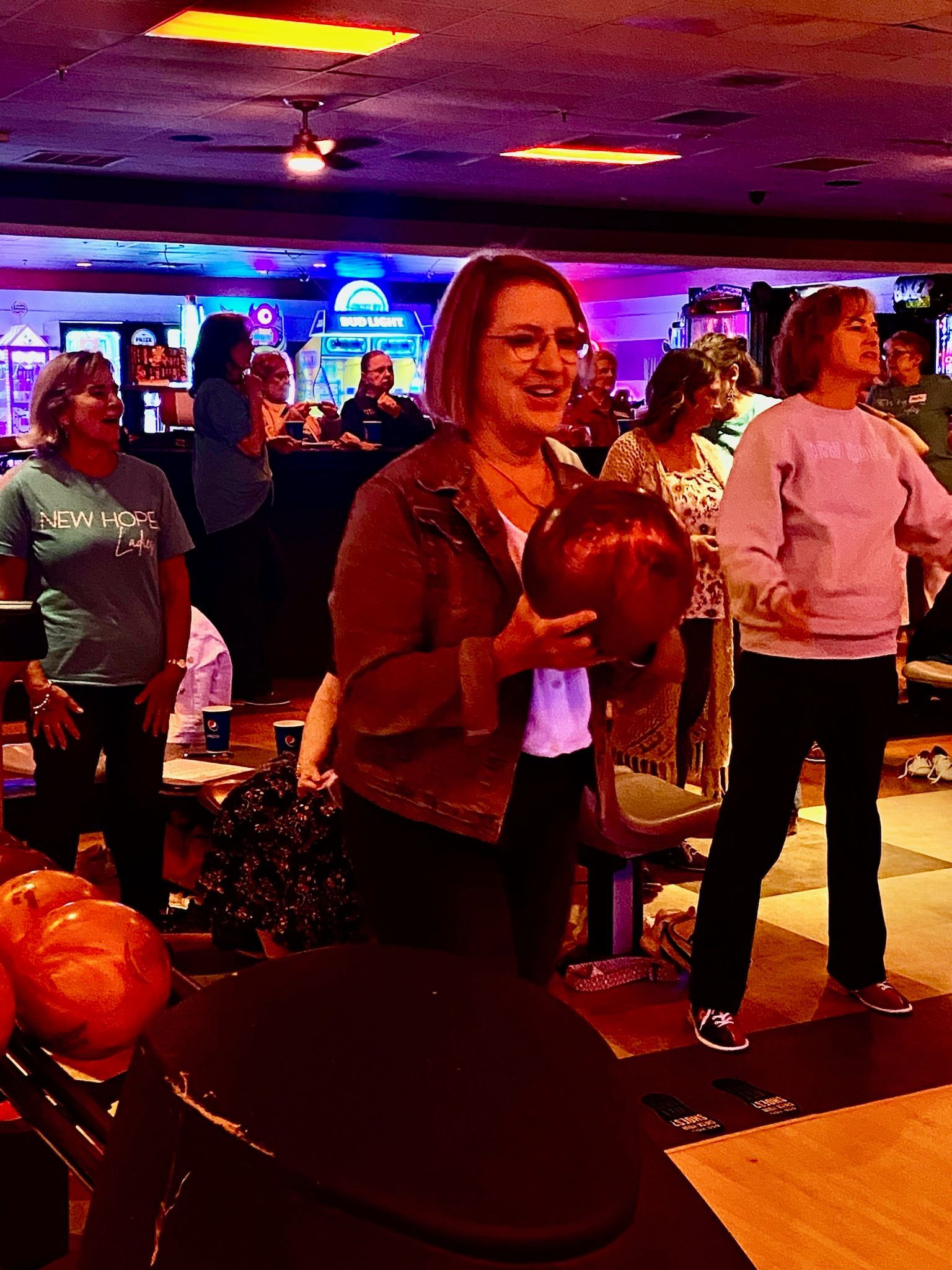 A woman is holding a bowling ball in a bowling alley