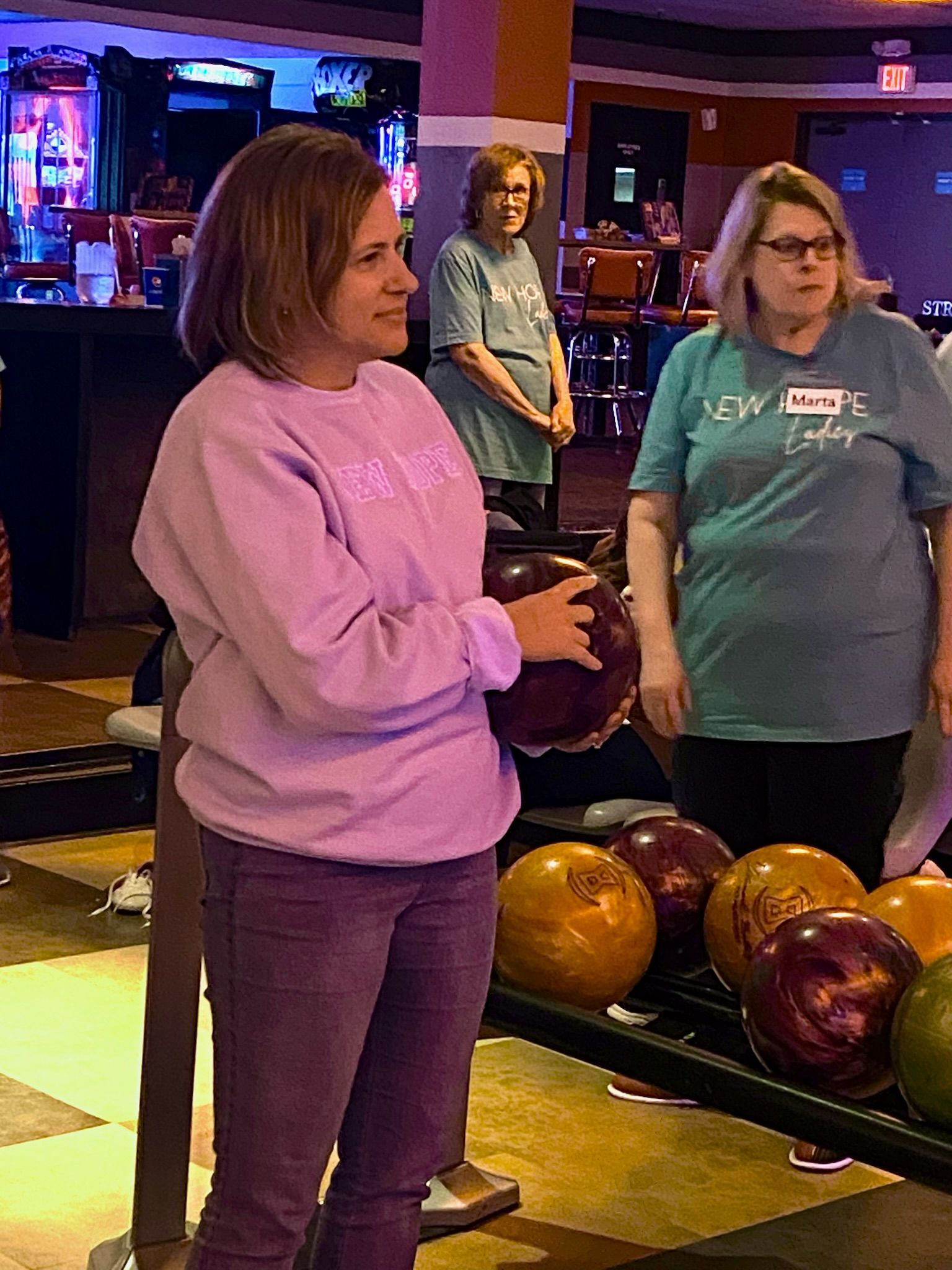 A woman is holding a bowling ball in a bowling alley.