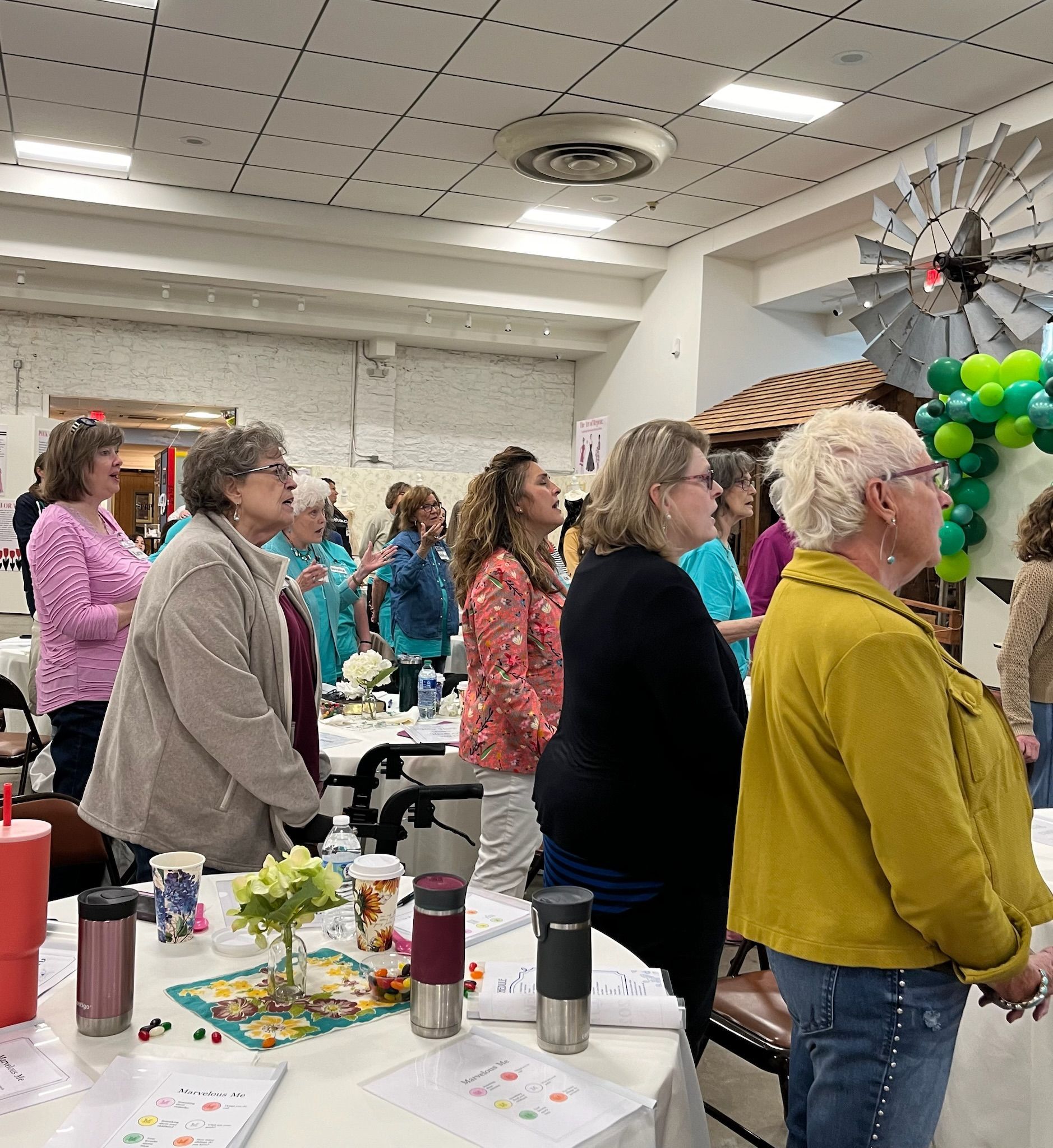 A group of people are standing around tables in a room.