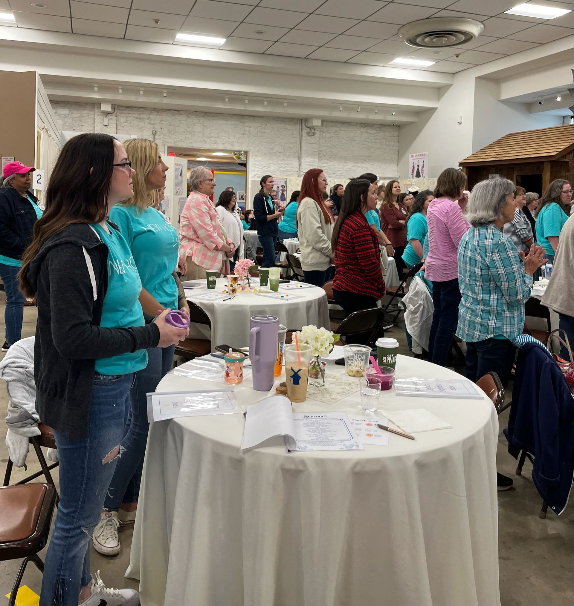 A group of people standing around tables in a room