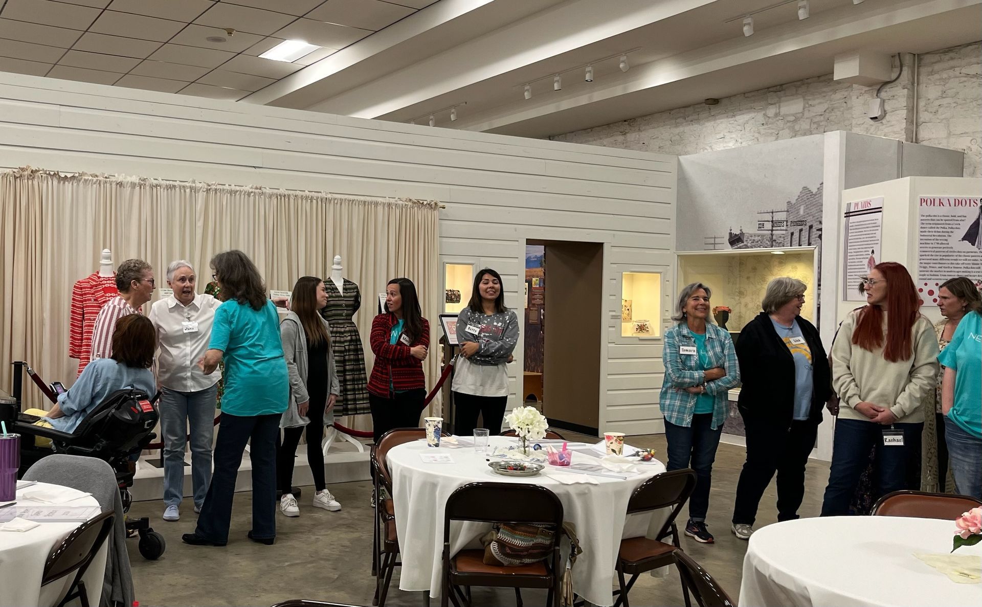 A group of people are standing around tables in a room.