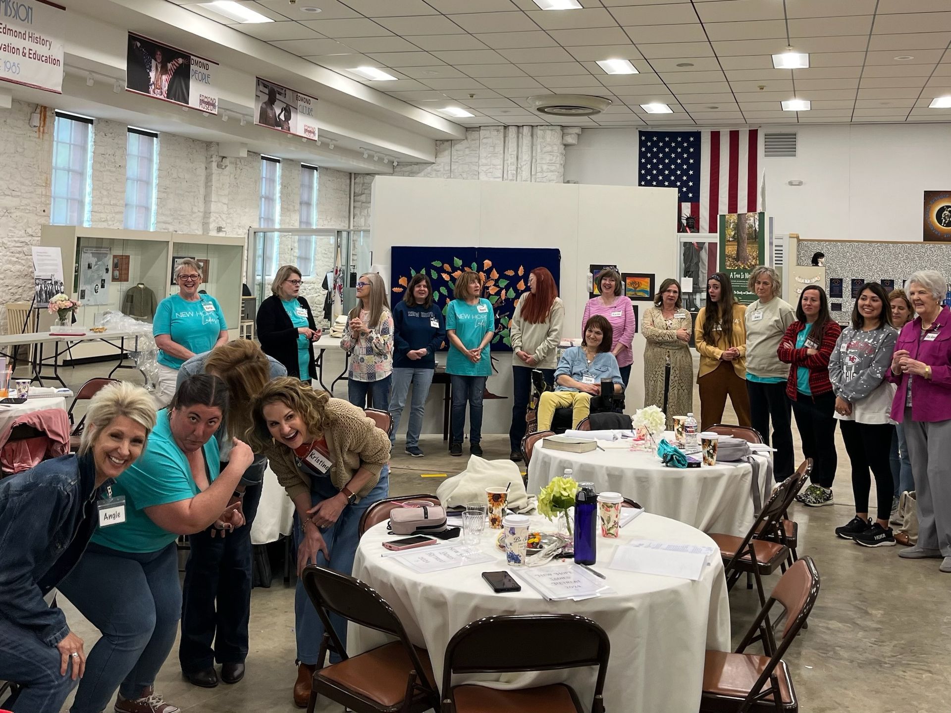 A group of women are posing for a picture in a room with tables and chairs.