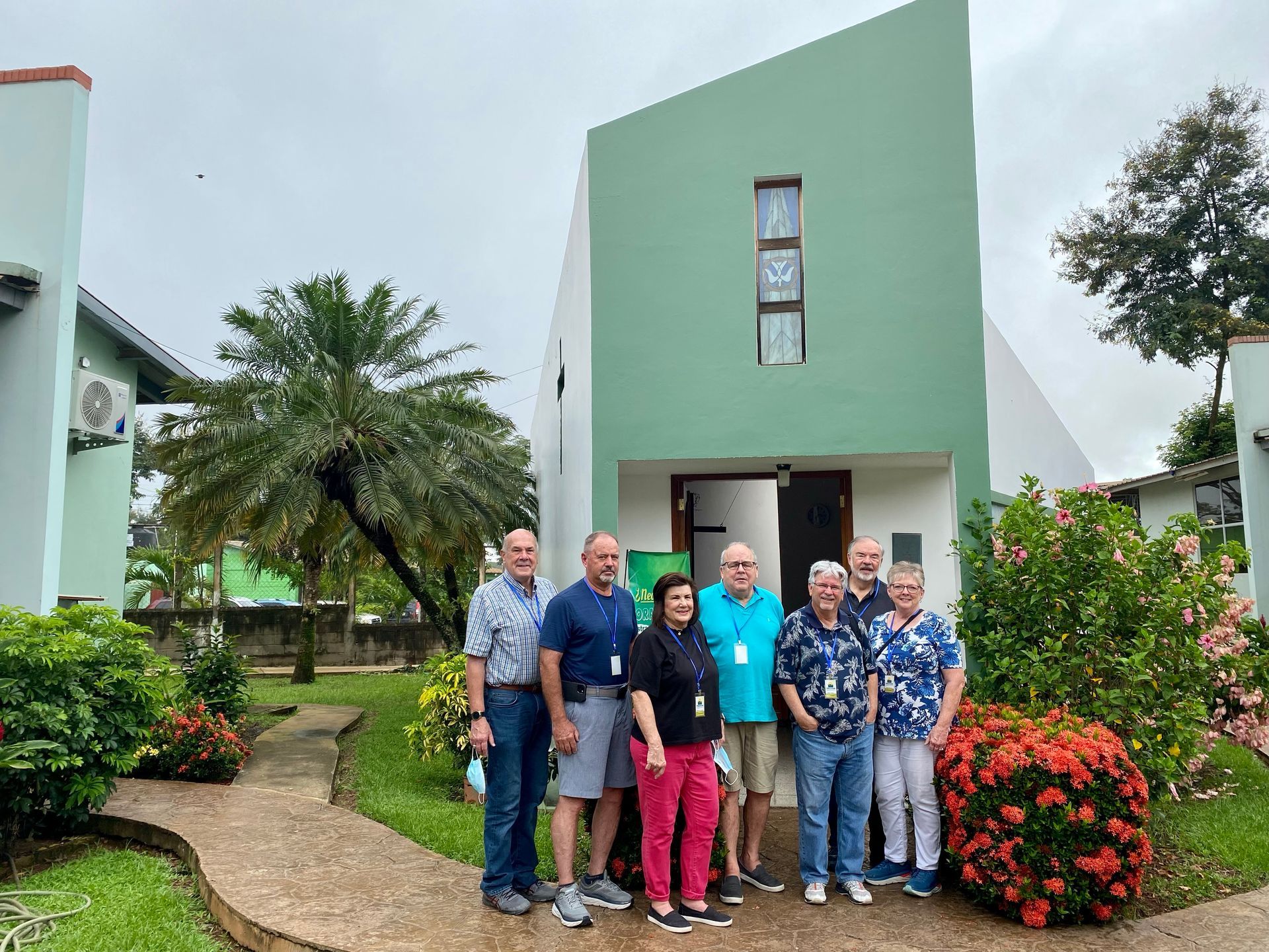 A group of people are posing for a picture in front of a green house.