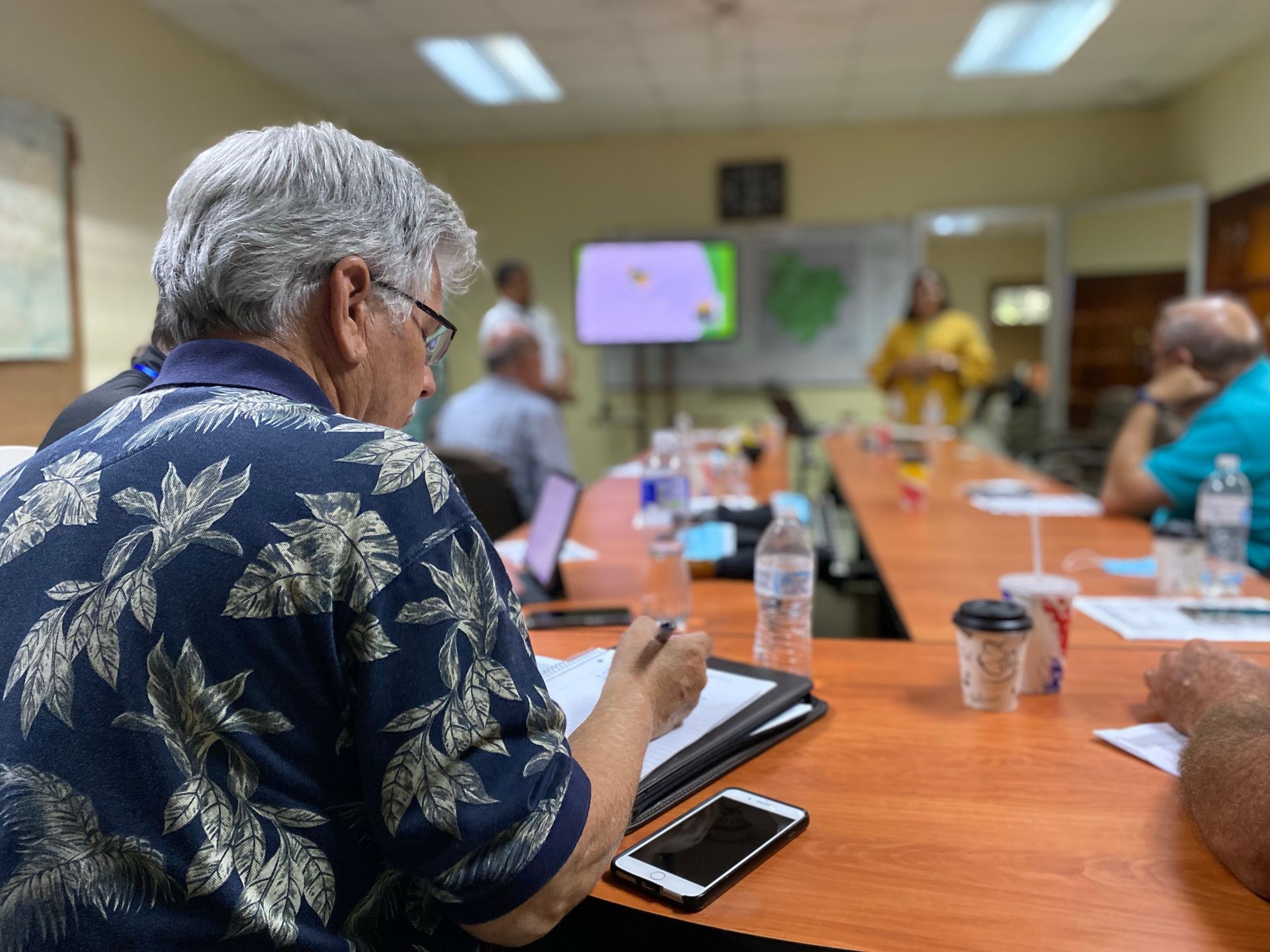 A group of people are sitting at a long table in a conference room.