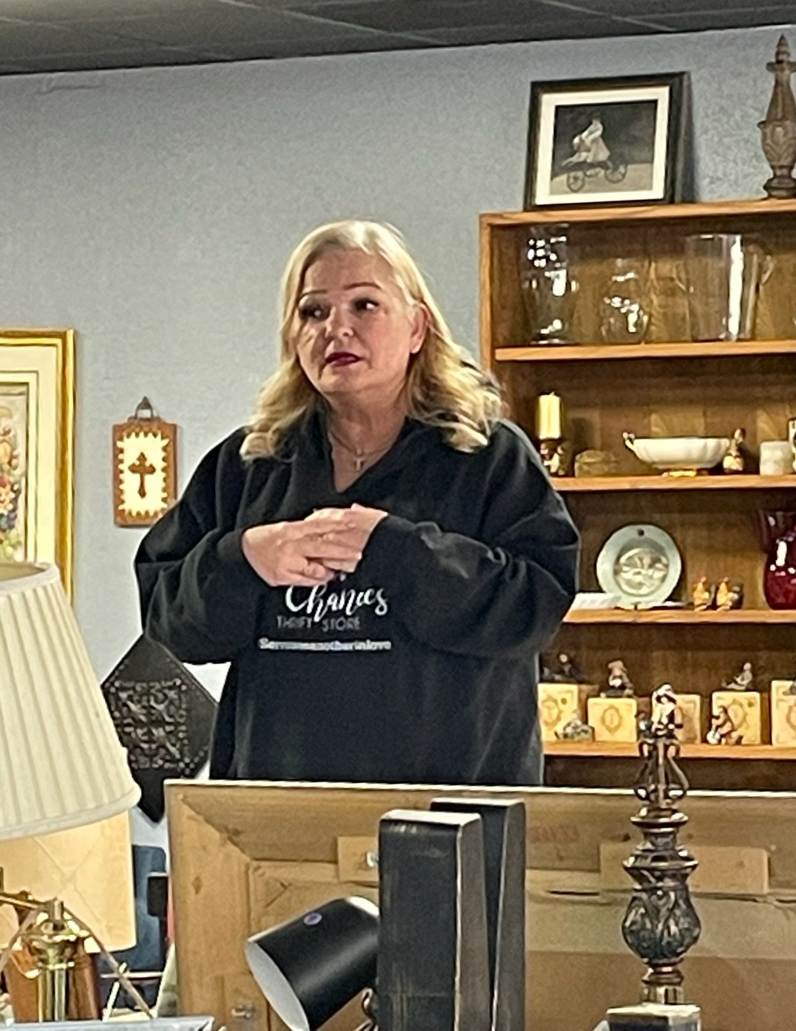 A woman is standing in front of a shelf with a picture on it.