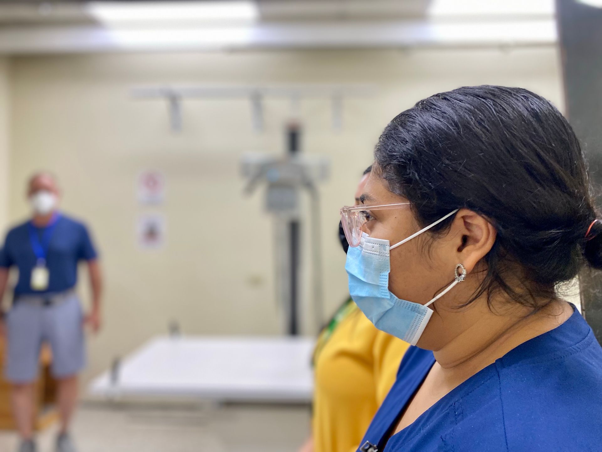 A woman wearing a mask and glasses is standing in a room.