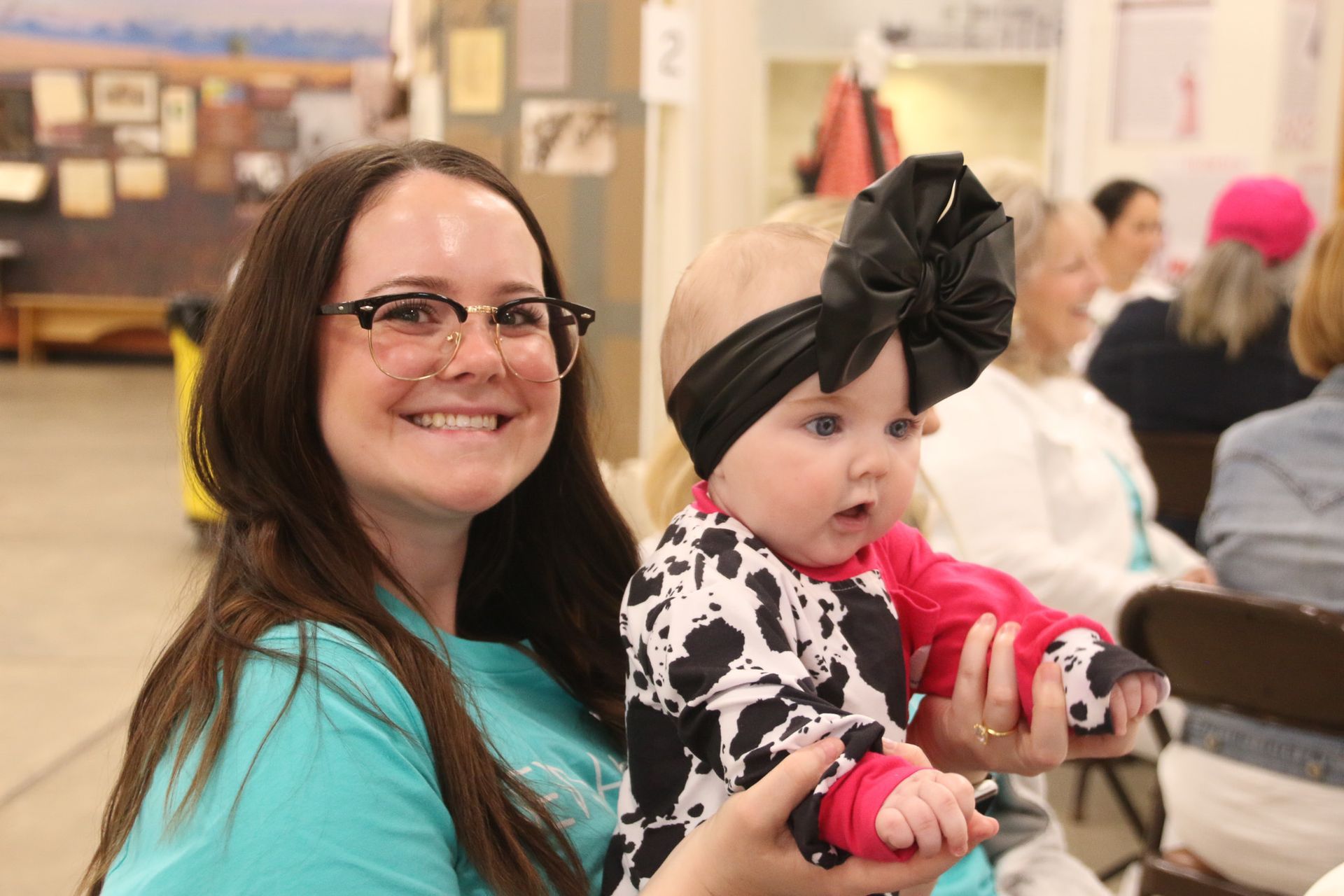 A woman is holding a baby in her arms and smiling at the camera.