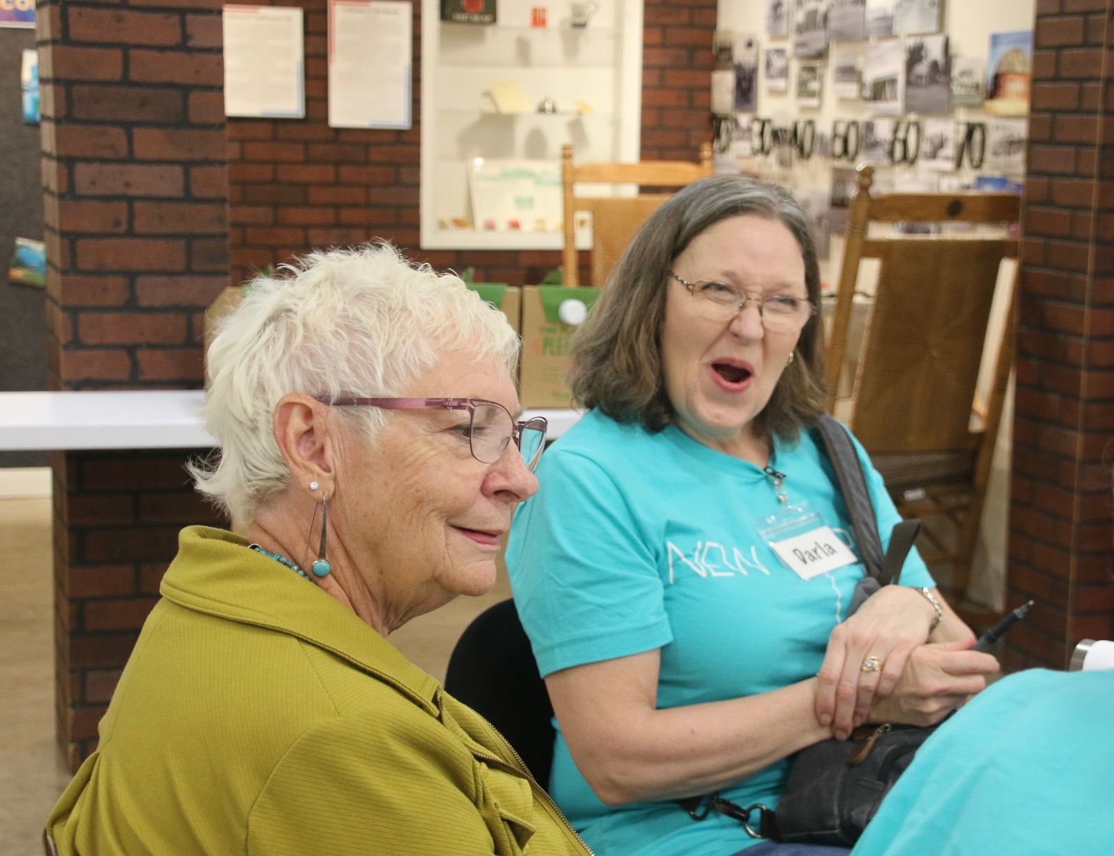 Two women are sitting next to each other and one has a name tag that says mom