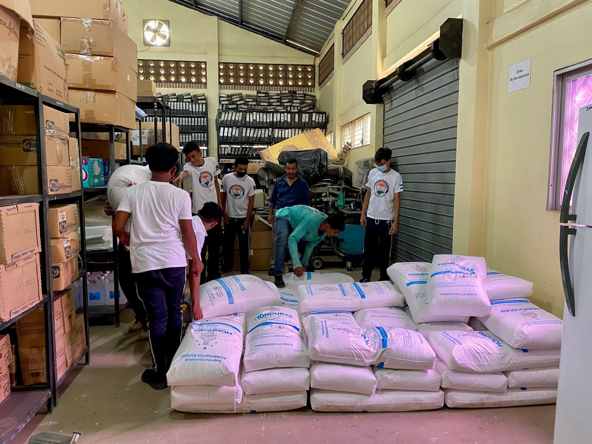 A group of people are standing around a pile of bags in a warehouse.