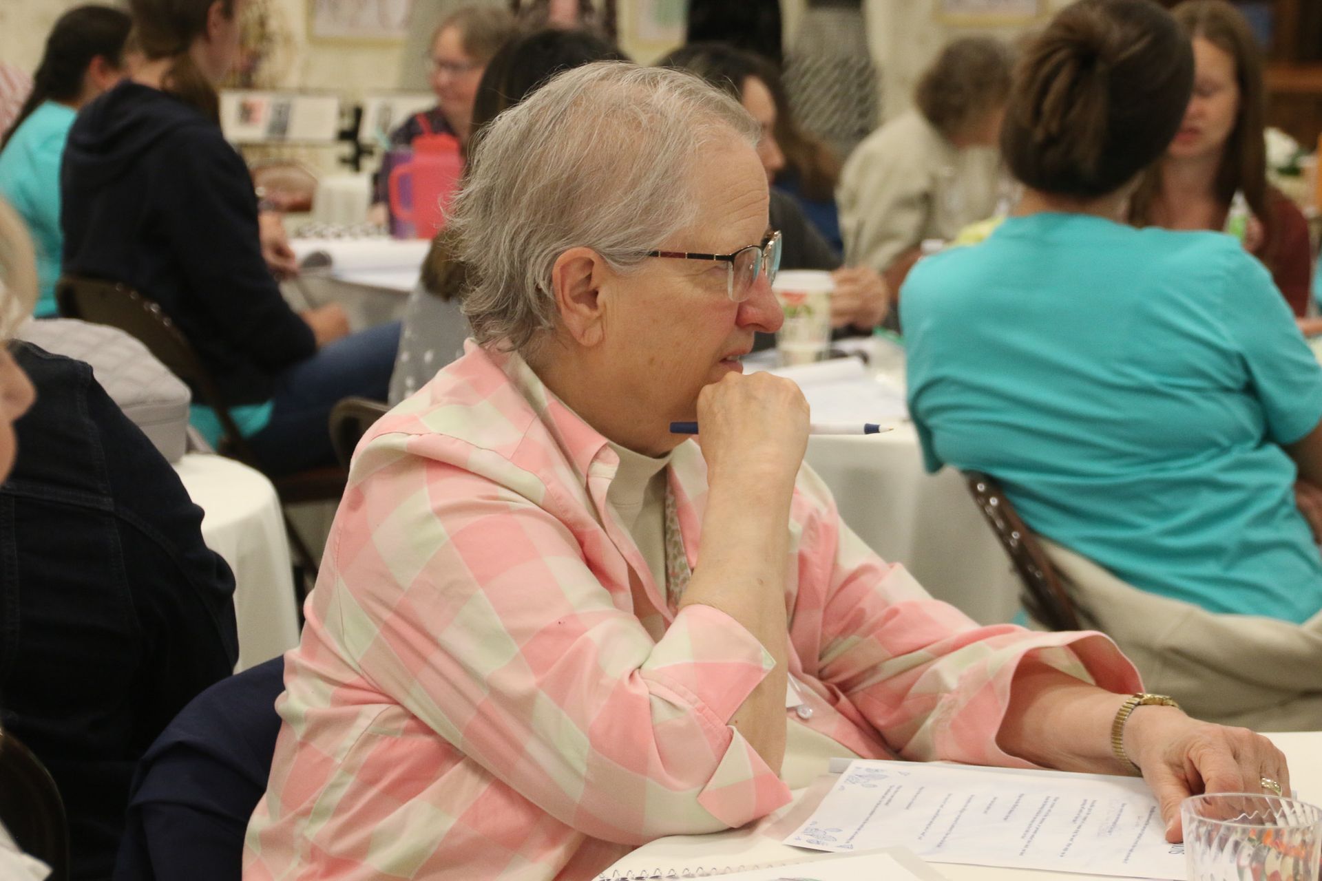 A woman is sitting at a table with her hand on her chin.