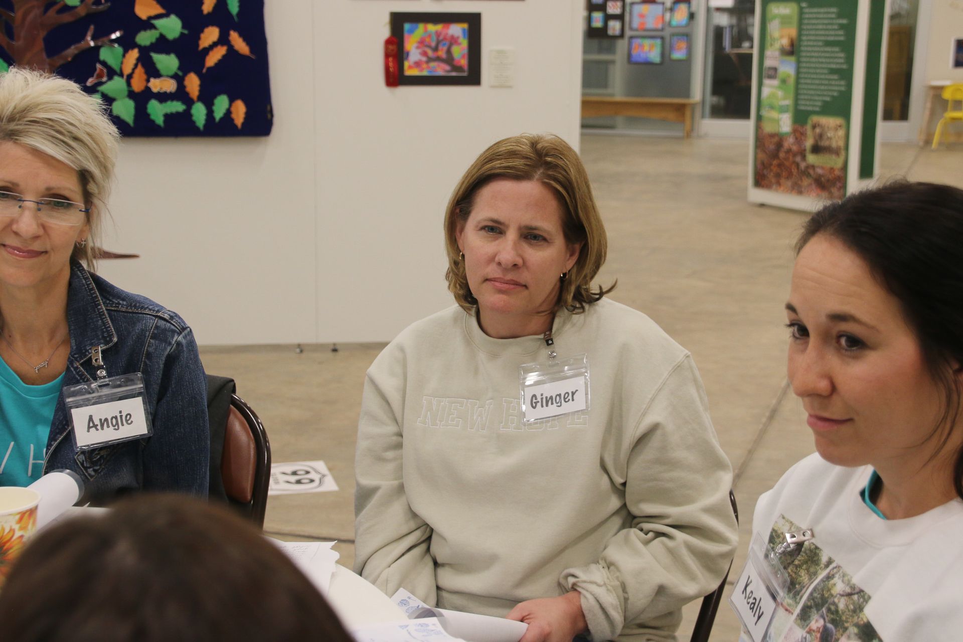 Three women are sitting at a table and one of them has a name tag that says amor