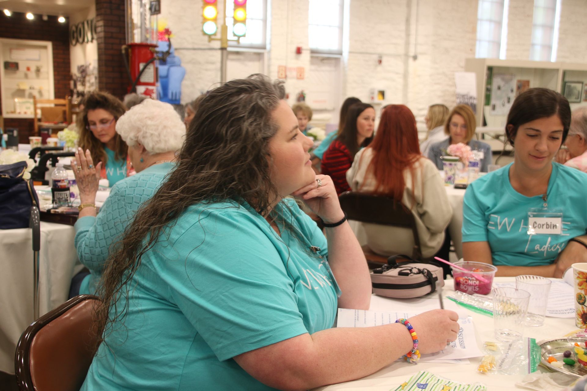 A woman in a blue shirt is sitting at a table with other people.