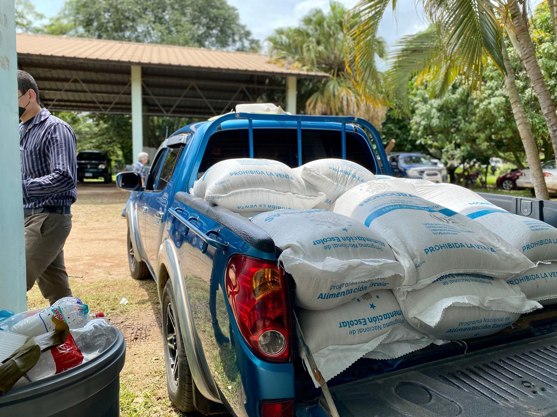 A blue truck is loaded with bags of rice.