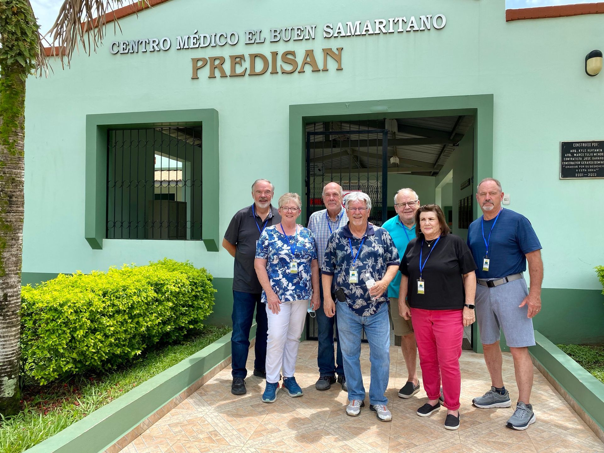 A group of people standing in front of a building that says predisan