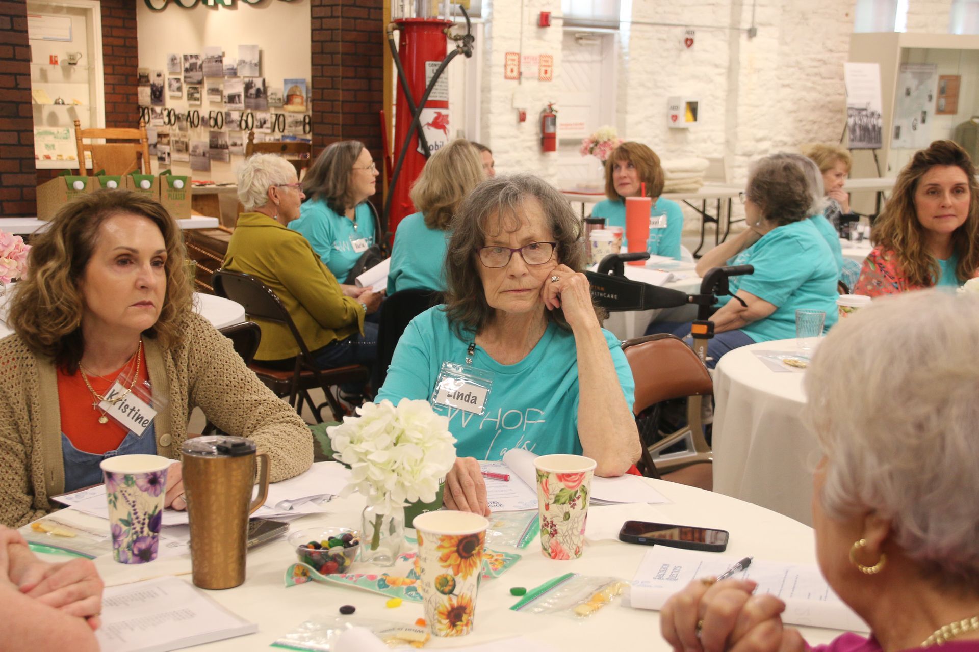 A group of women are sitting at tables in a room.