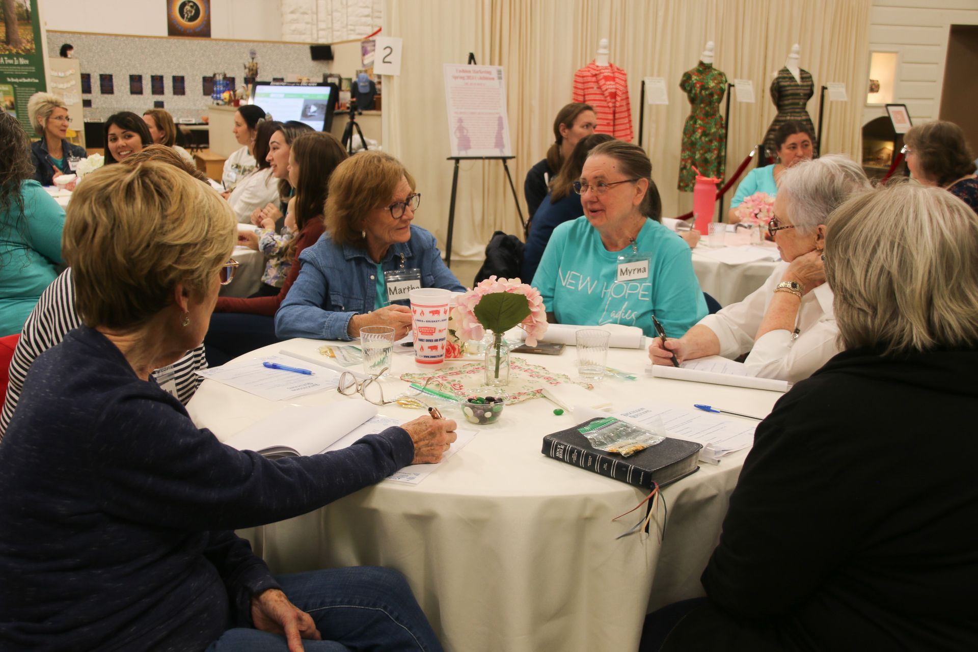 A group of women are sitting around a table with a book on it.