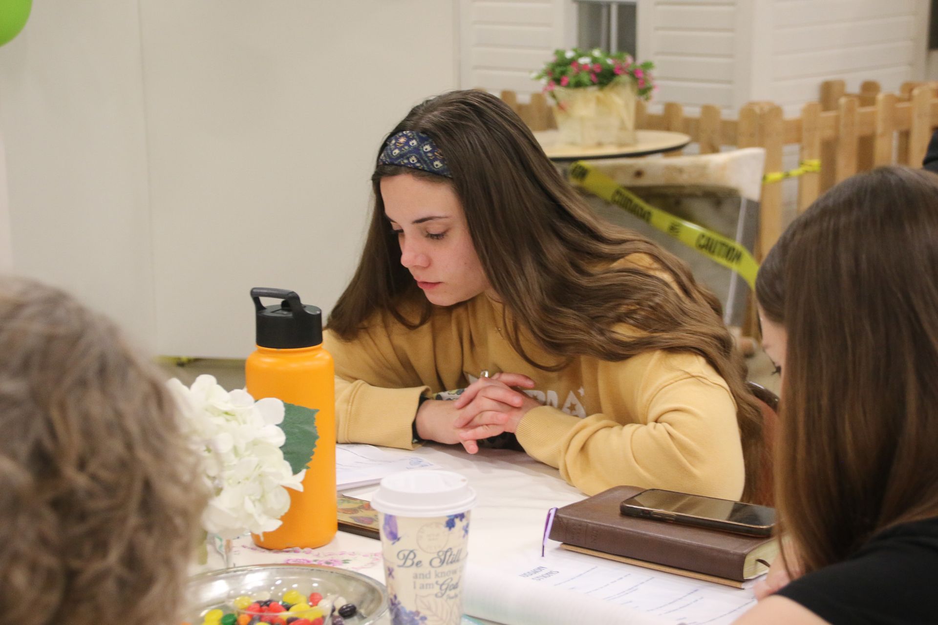 A girl is sitting at a table with a water bottle and a bible.