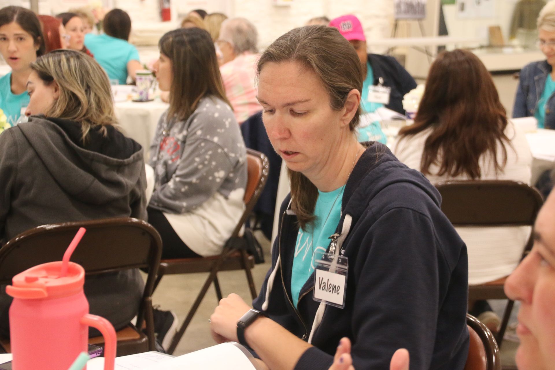 A woman wearing a name tag is sitting at a table with other people.