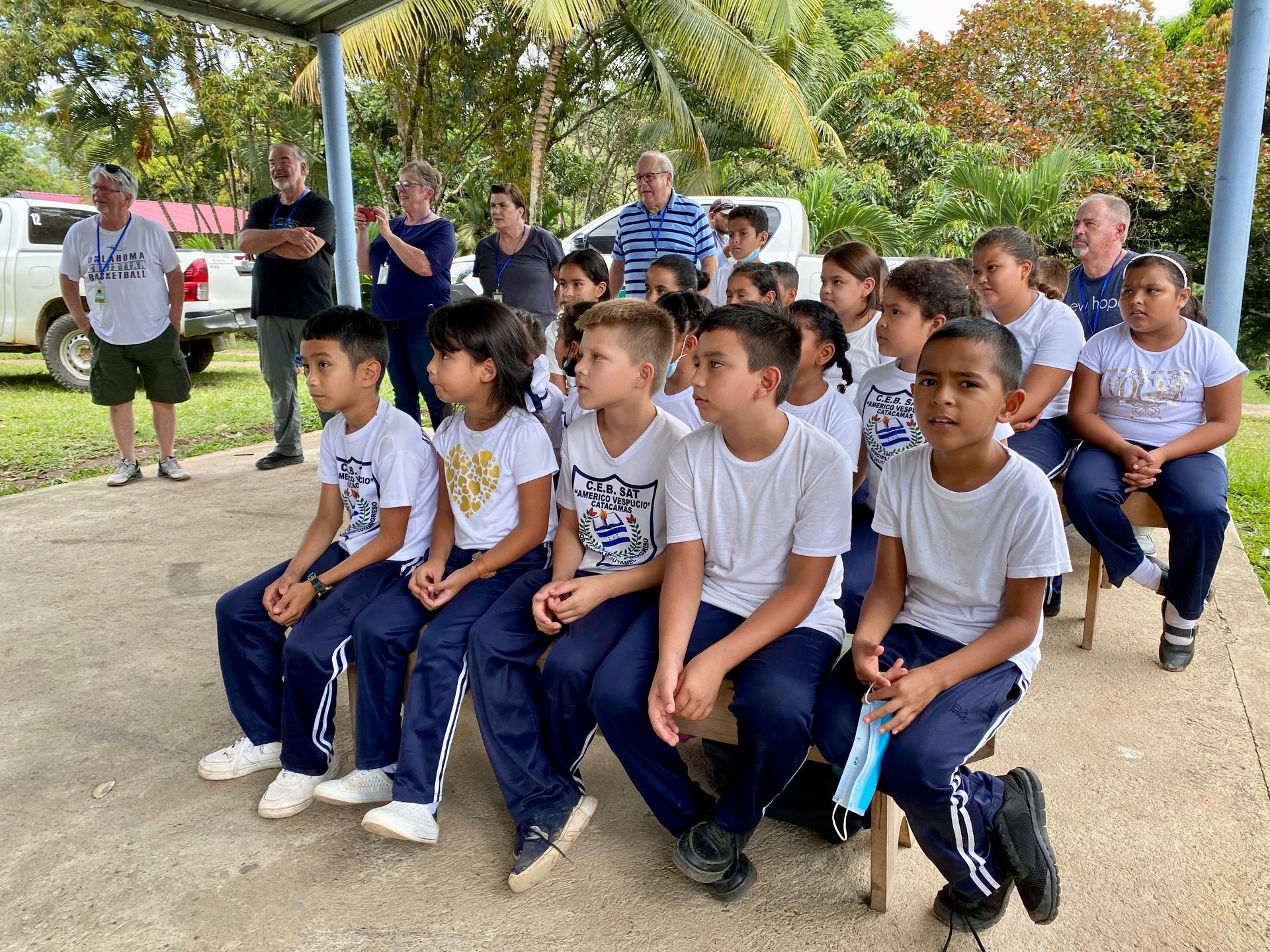 A group of children in school uniforms are sitting on a bench.