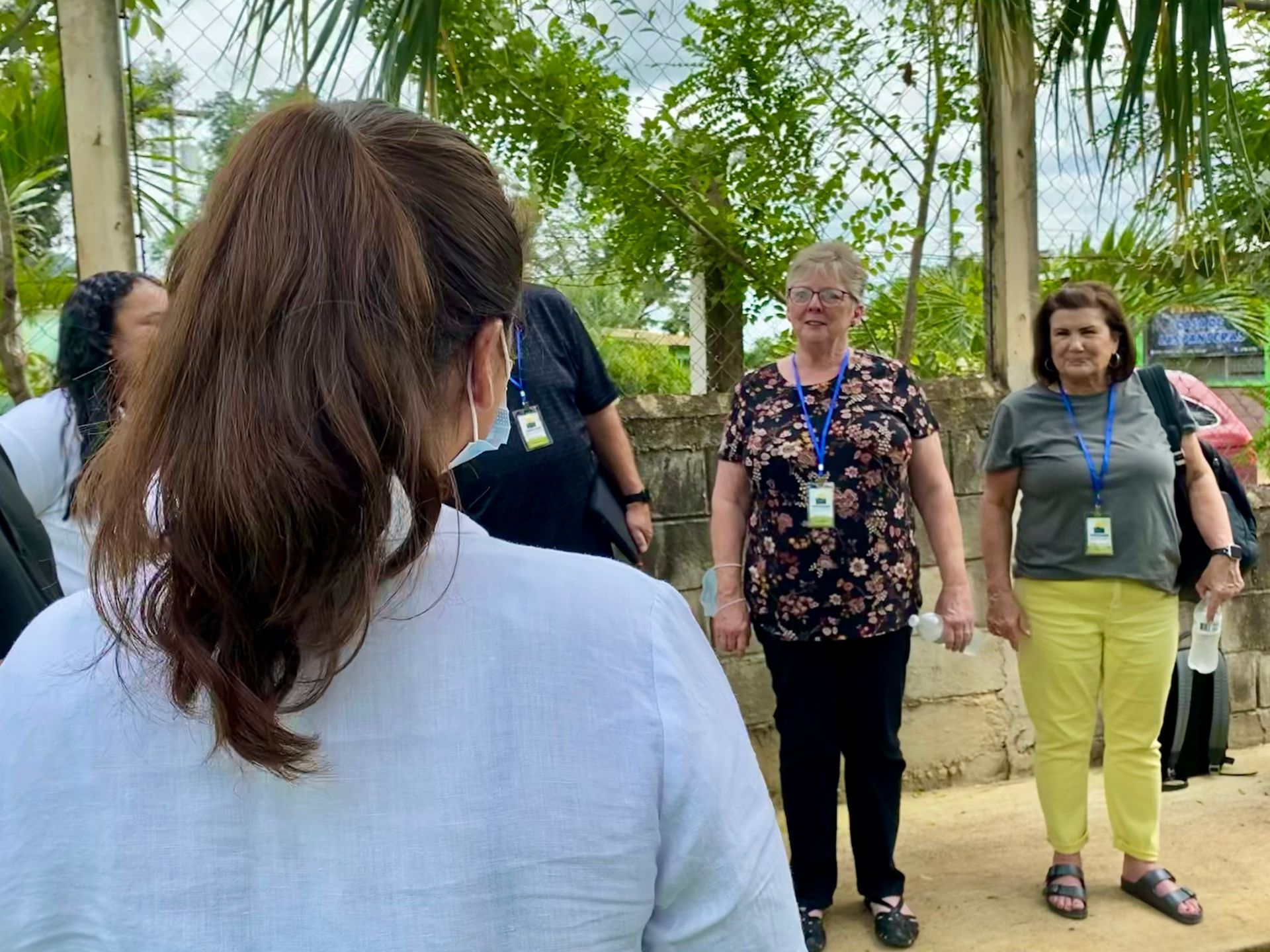 A woman wearing a mask is standing in front of a group of people.