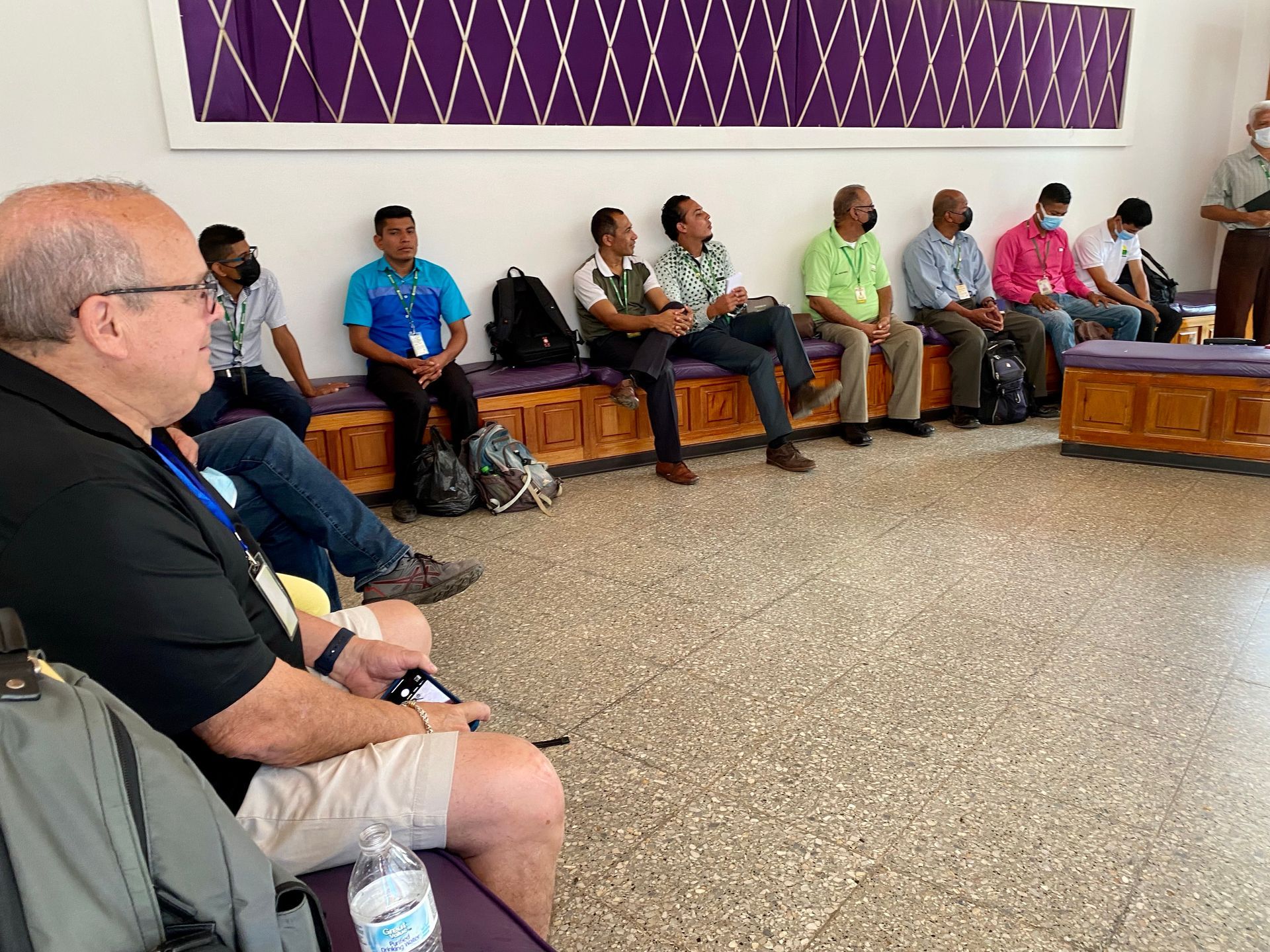 A group of people are sitting on benches in a waiting room.