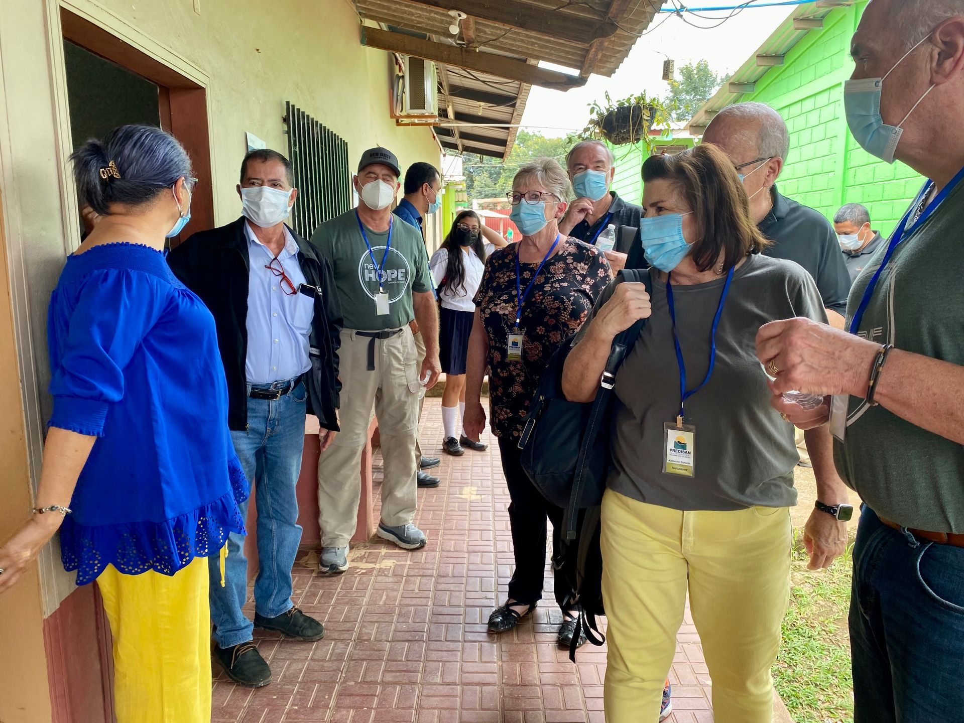 A group of people wearing face masks are standing outside of a building.