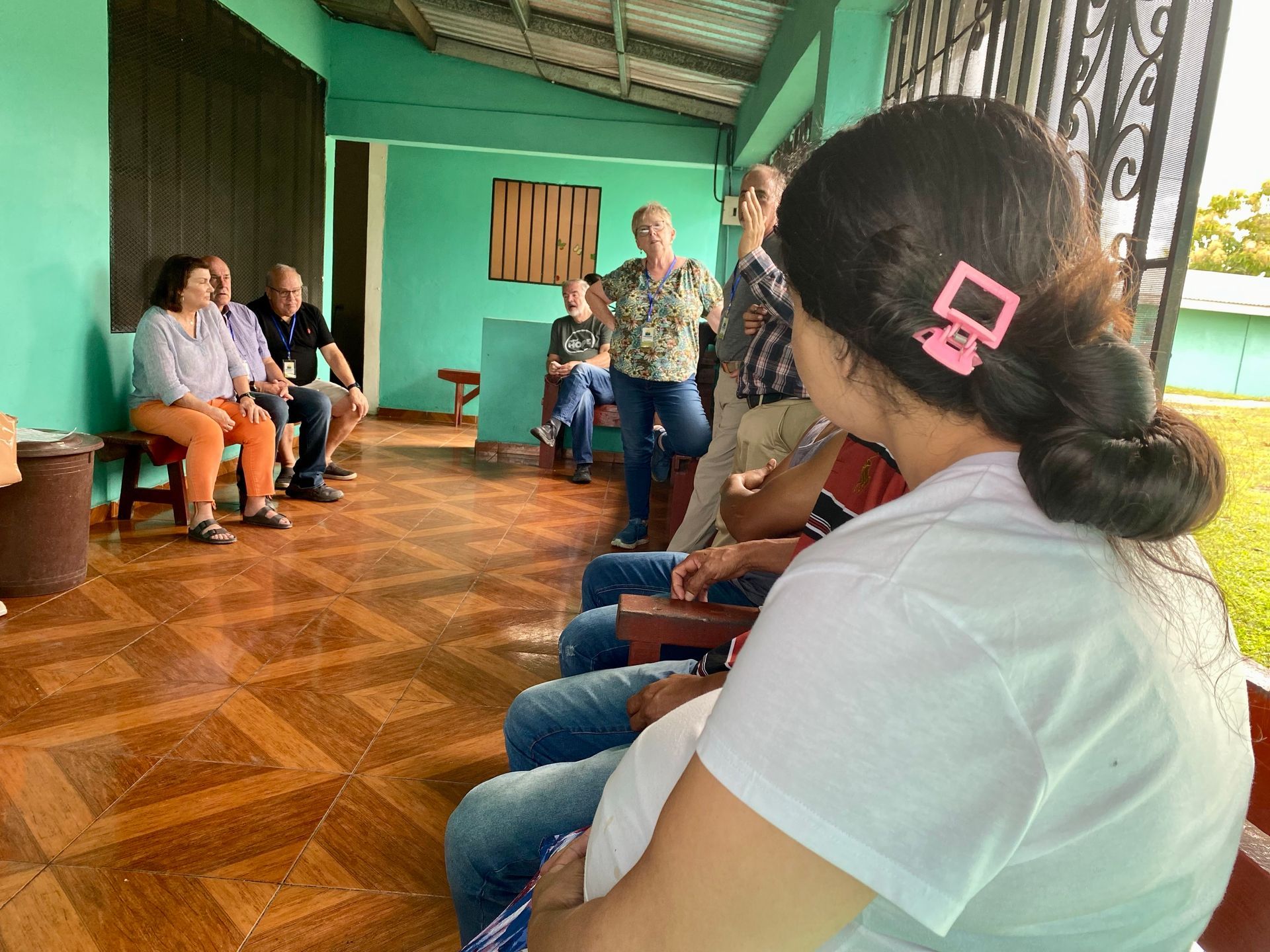 A group of people are sitting on a porch talking to each other.