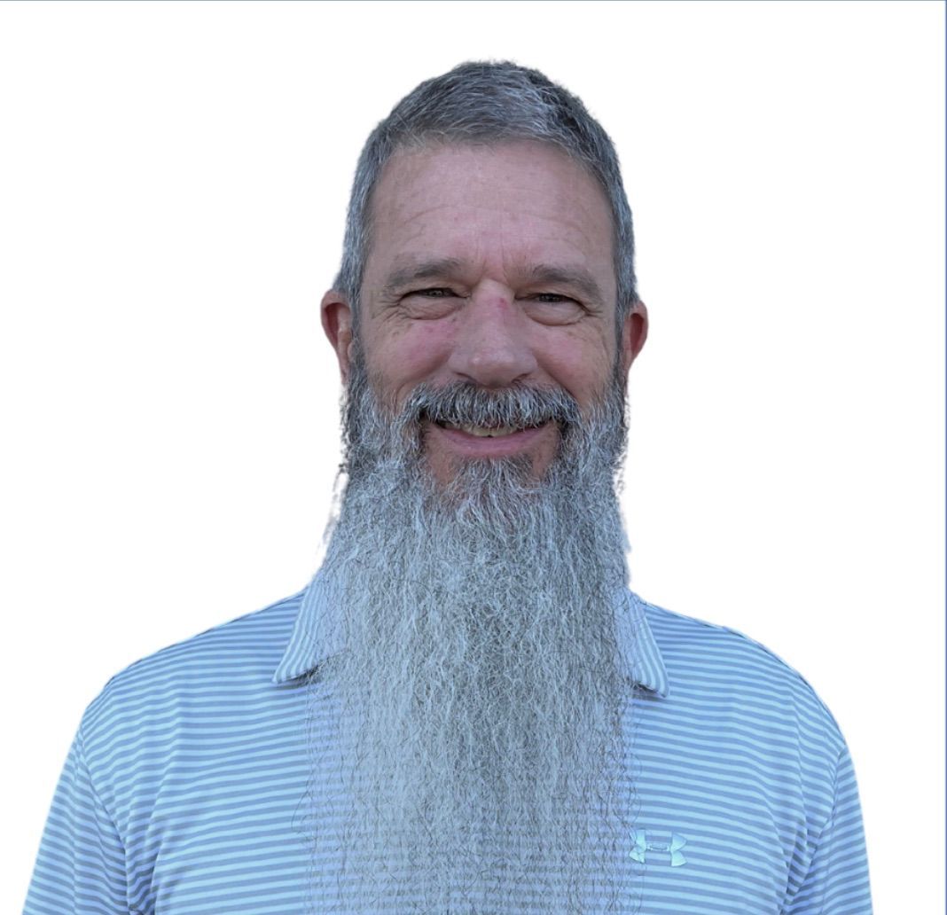 A man in a red shirt is smiling for the camera