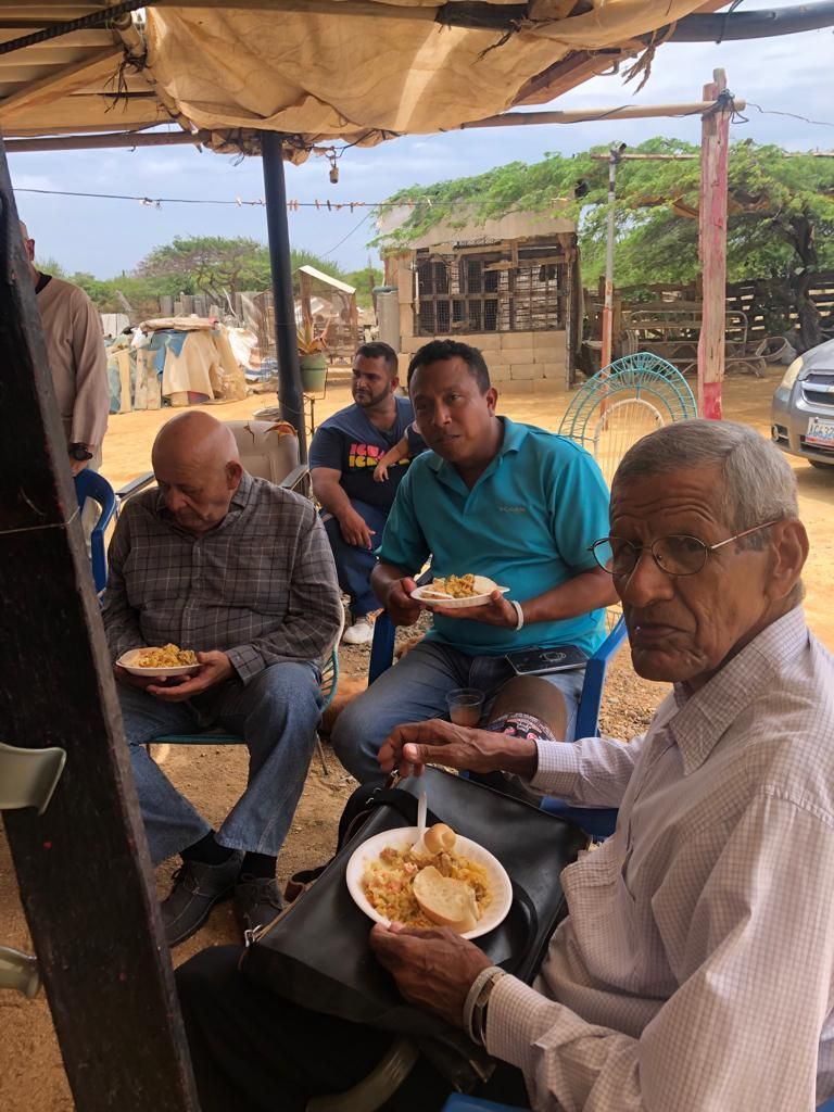 A group of men are sitting in chairs eating food.