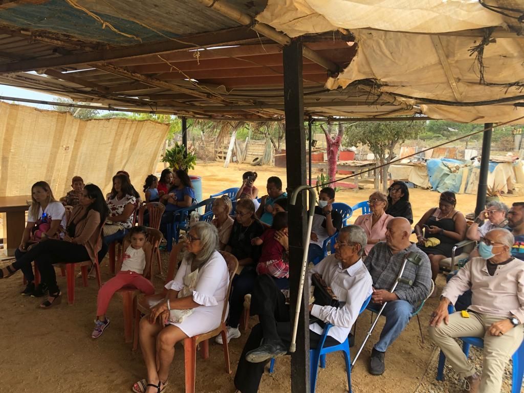 A group of people are sitting in chairs under a canopy.