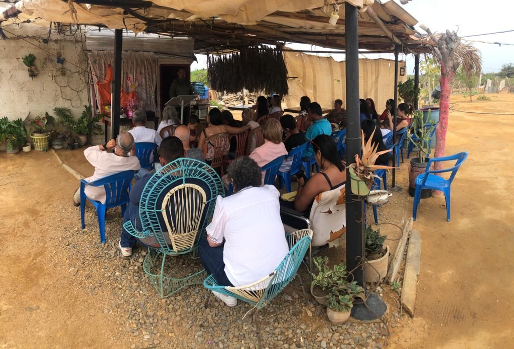 A group of people are sitting in chairs under a canopy.