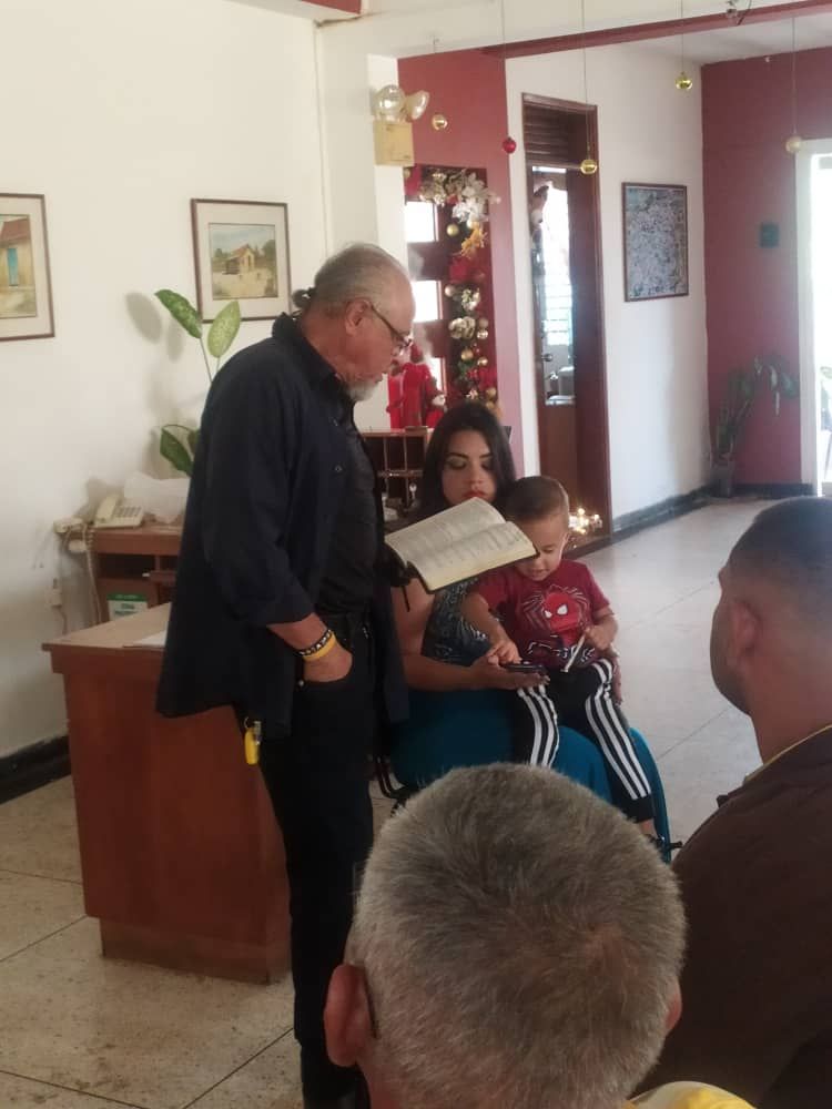 A man is reading a book to a woman and a child