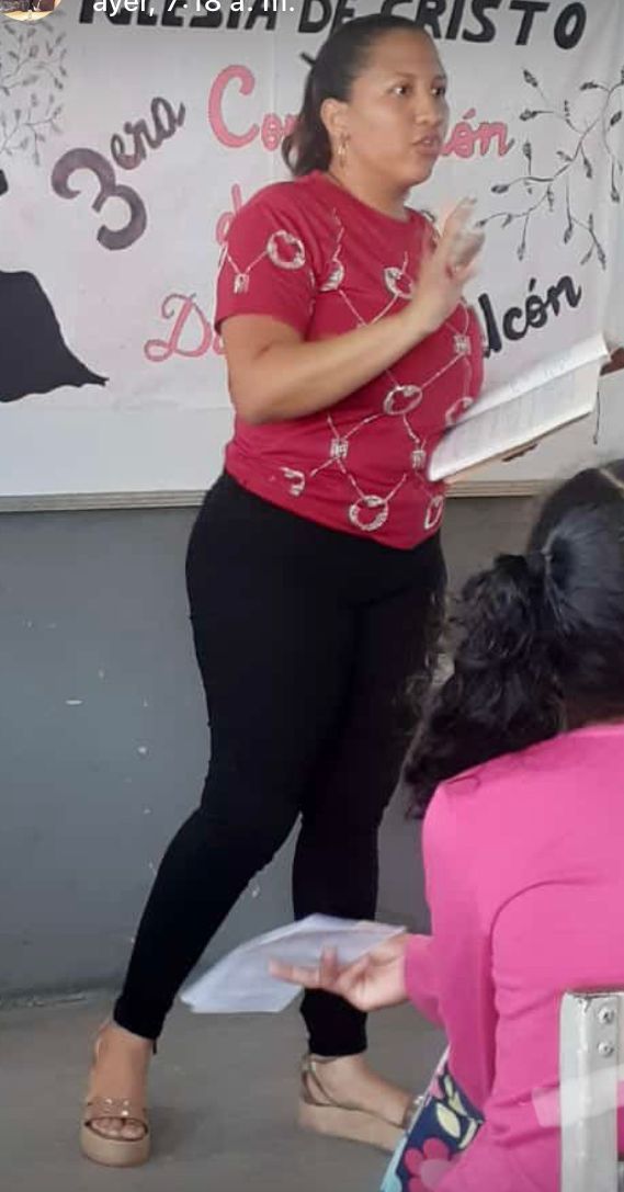 A woman in a red shirt is standing in front of a sign that says zona