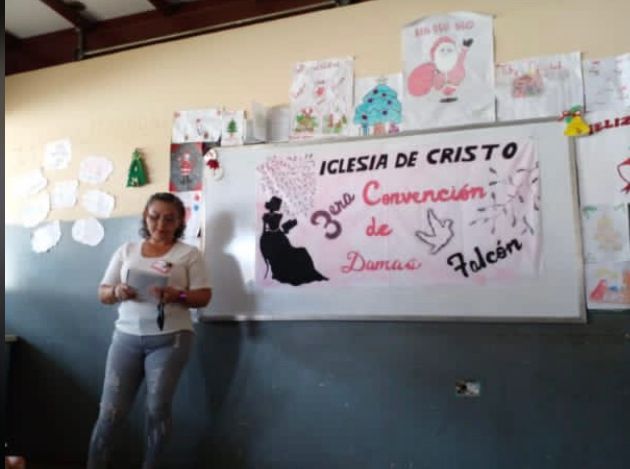 A woman stands in front of a white board that says iglesia de cristo