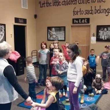 A group of children are standing in a room with a sign that says 