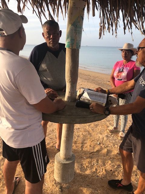 A group of people standing on a beach under an umbrella