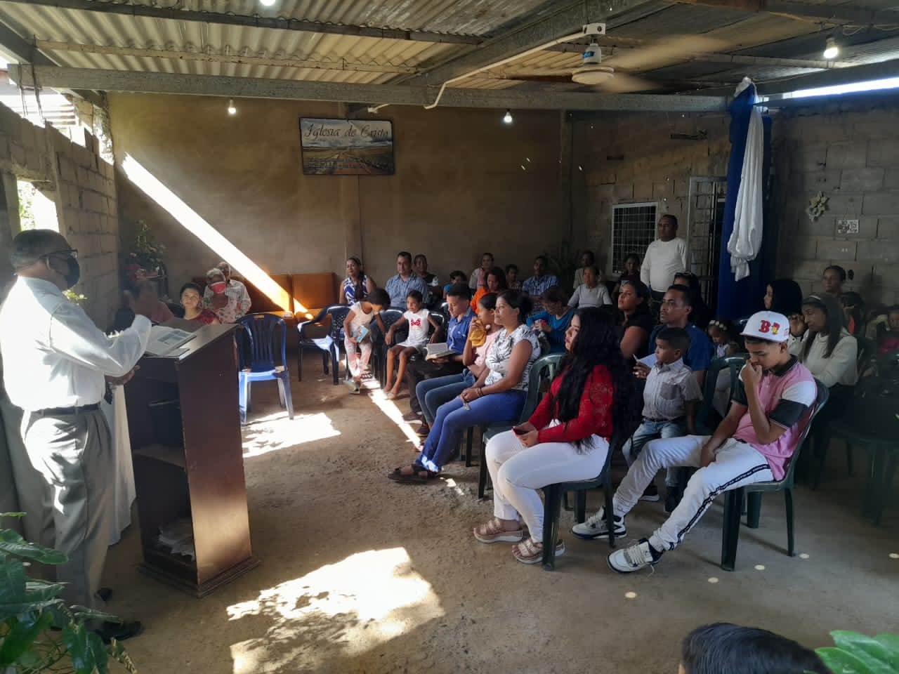 A man is giving a speech to a group of people sitting in chairs.