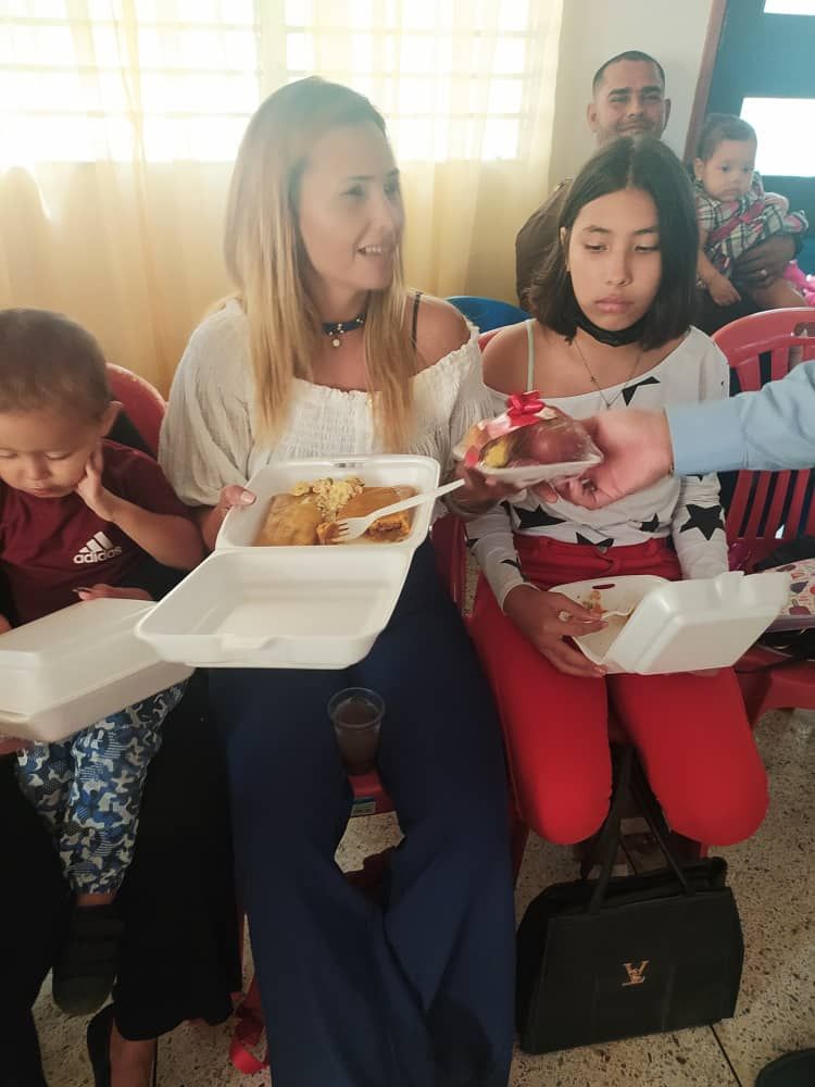 A group of people sitting in chairs holding styrofoam containers of food.