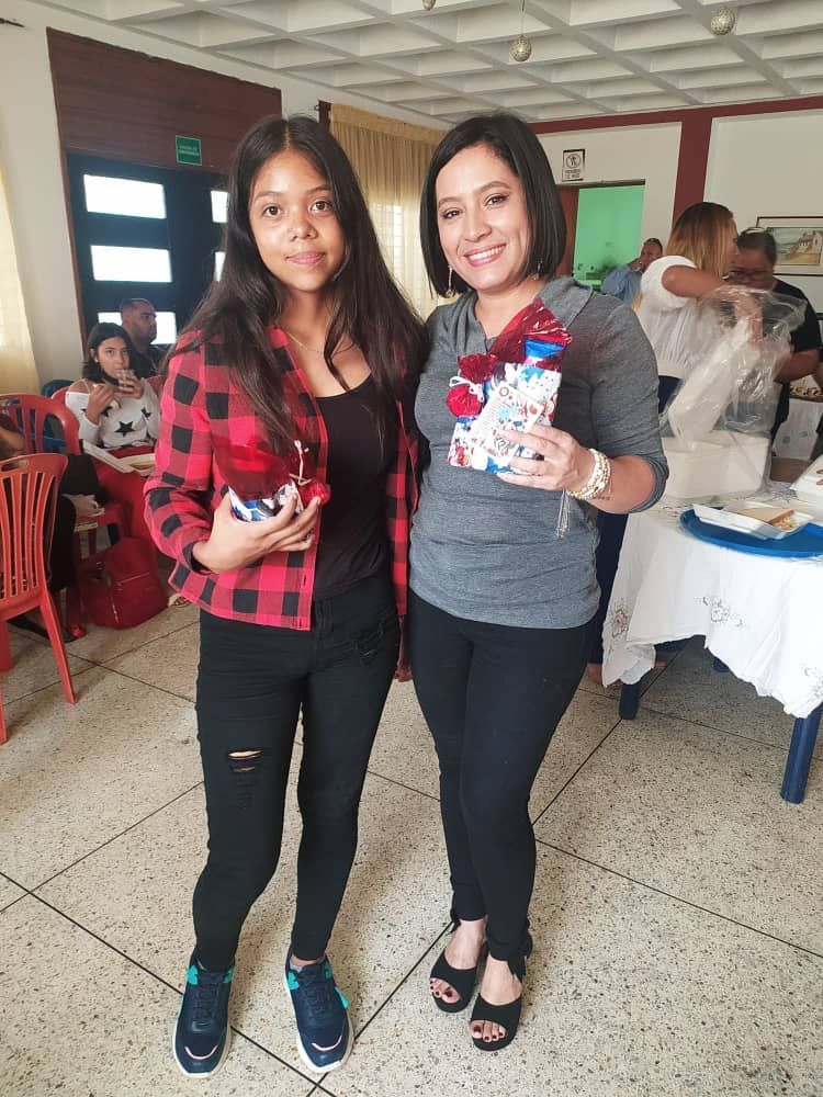 Two women are standing next to each other in a room holding bottles.
