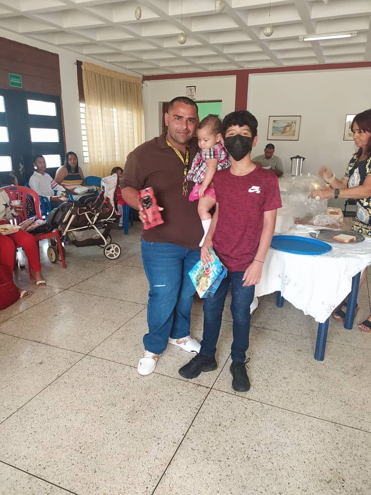 A man is holding a baby in a room with other people.