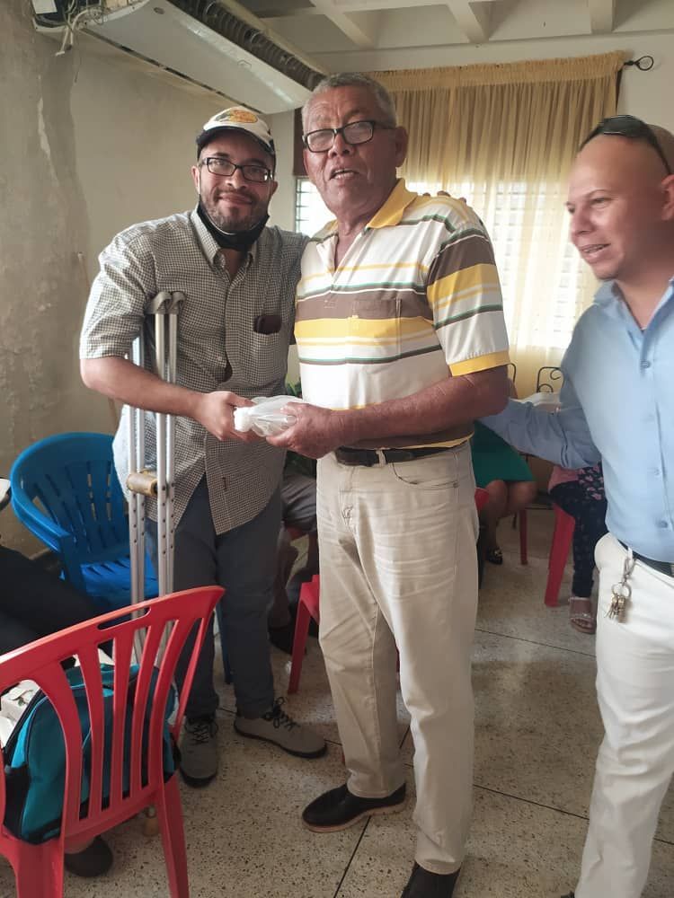 A man with crutches is shaking hands with another man in a room.