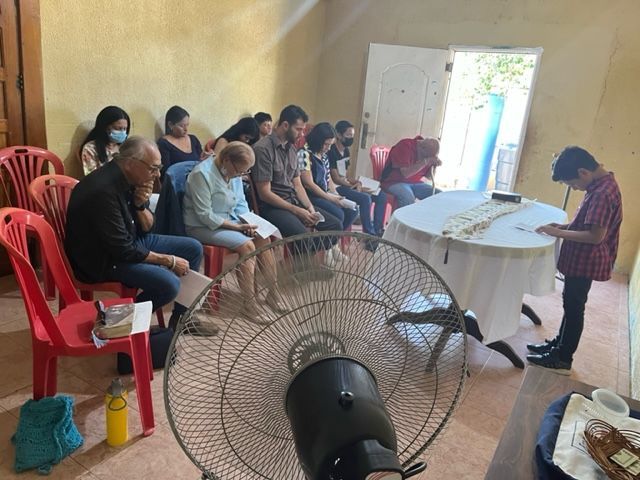 A group of people sitting around a table with a fan in the foreground