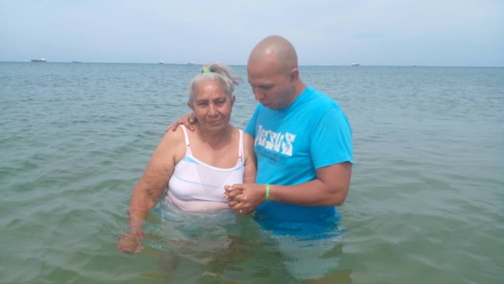 A man and a woman are standing in the ocean.