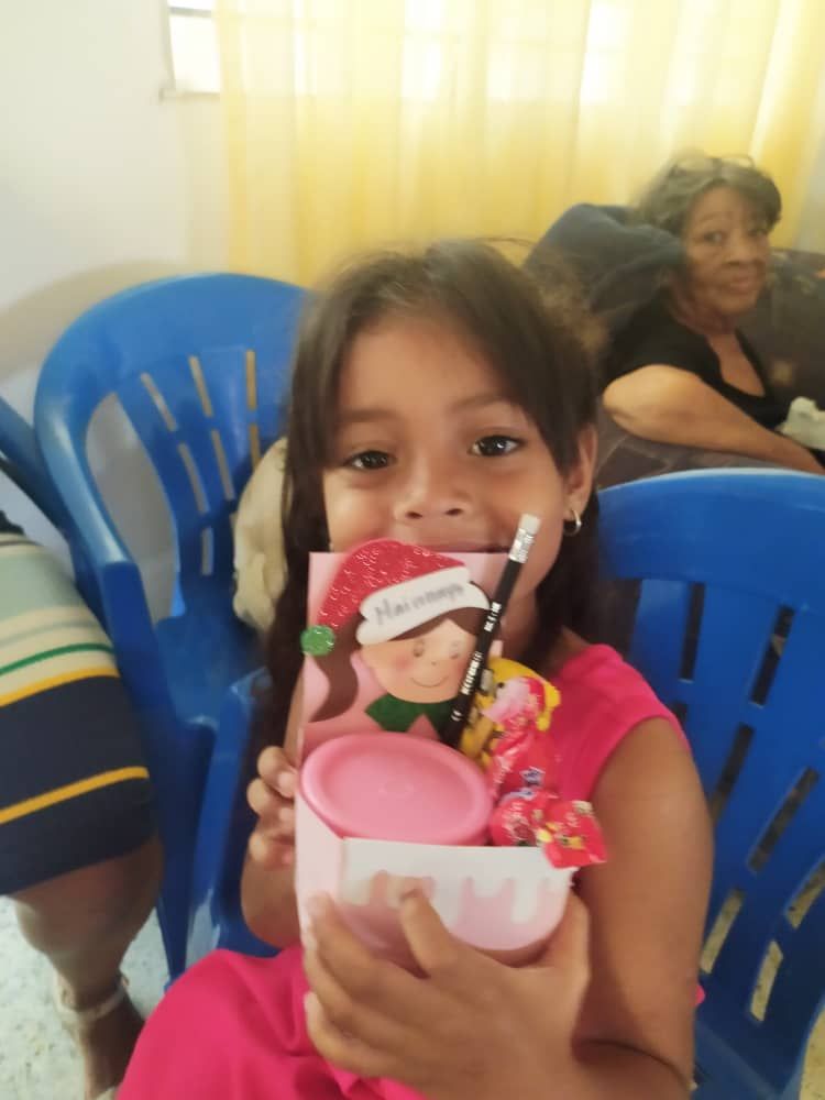 A little girl is sitting in a blue chair holding a card and a cup