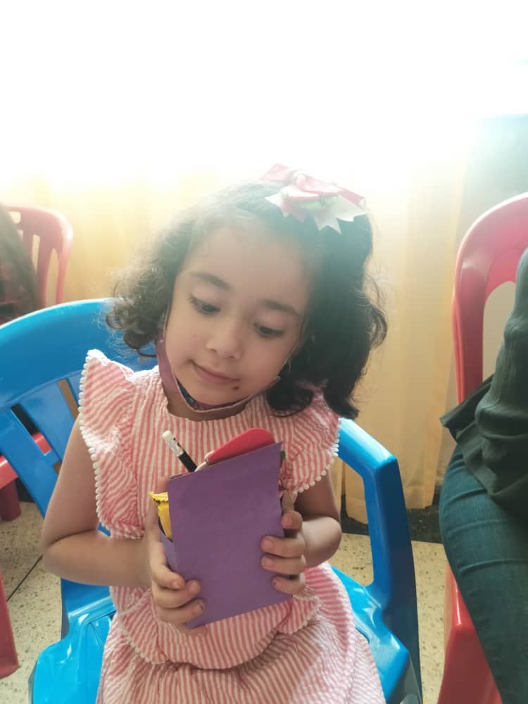 A little girl is sitting in a blue chair reading a book