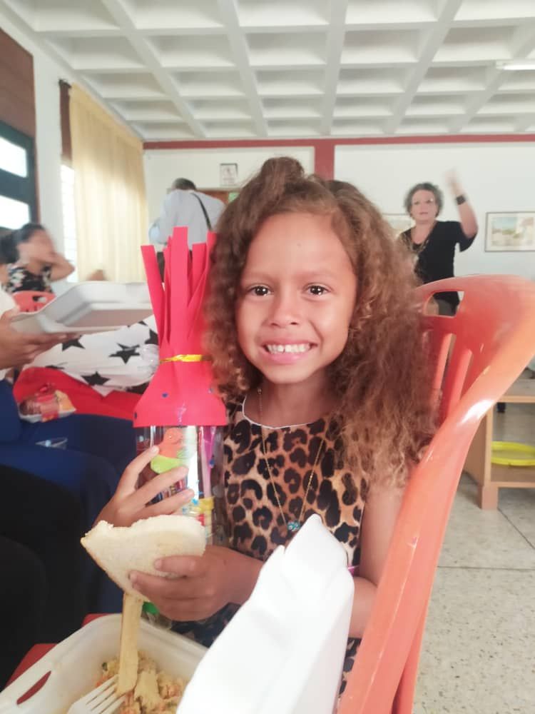 A little girl in a leopard print dress is sitting in an orange chair