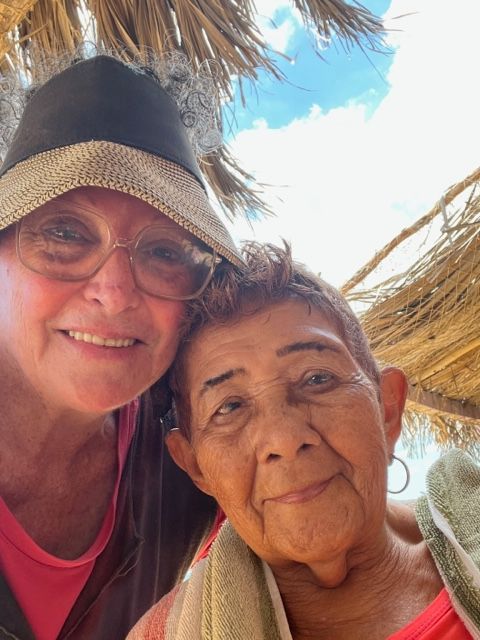 Two women are posing for a picture under an umbrella