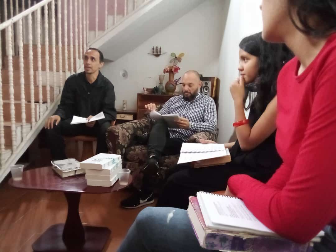 A group of people are sitting around a table with books on it