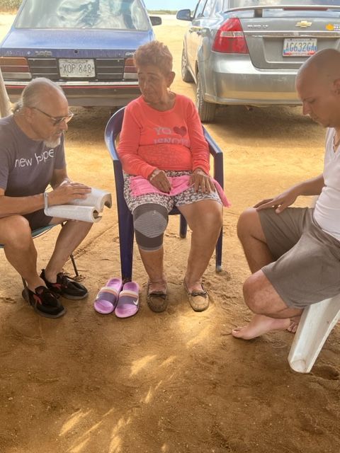 A group of people are sitting in chairs on the ground talking to each other.
