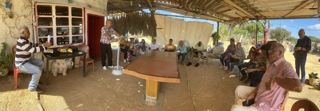 A group of people are sitting around a table under a canopy.